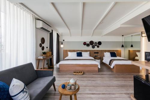 a hotel room with two beds and a couch at HOMM Boutique Hotel in Chiang Mai