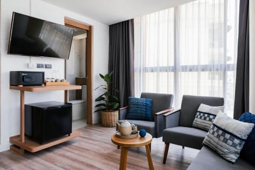 a living room with a tv and a couch and chairs at HOMM Boutique Hotel in Chiang Mai