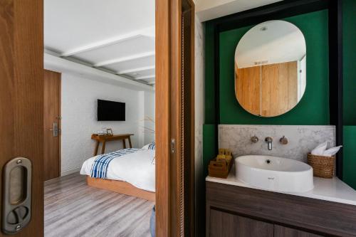 a bathroom with a sink and a bed and a mirror at HOMM Boutique Hotel in Chiang Mai