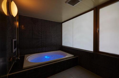 a bathroom with a large tub with blue water at HOTEL LOVE in Nagoya