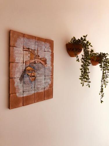 a painting on a wall next to two plants at Little Paradise in Taormina