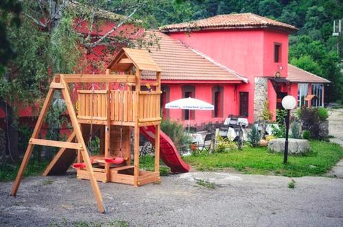 a wooden playground with a slide in front of a red house at Zlatna ribka in Kokolyane