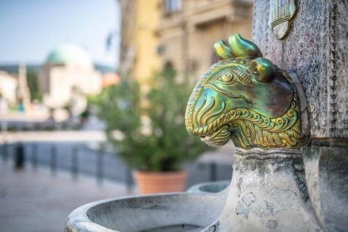 a brass elephant head sticking out of a vase at Presso Pécs in Pécs