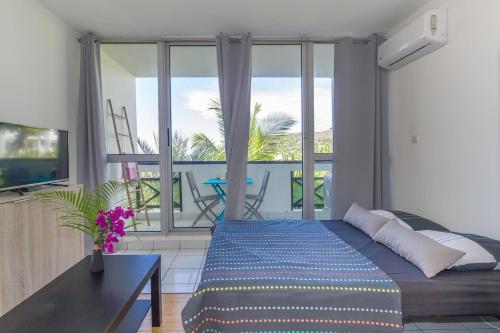 a living room with a bed and a balcony at Boucan Beach Joli studio vue mer à Boucan Canot in Boucan Canot