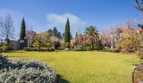 a large grassy yard with trees and buildings at Craigivar Guesthouse in Pretoria
