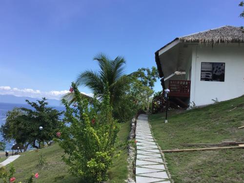 a house on a hill with a palm tree at Cuestas Beach Resort and Restaurant in Badian