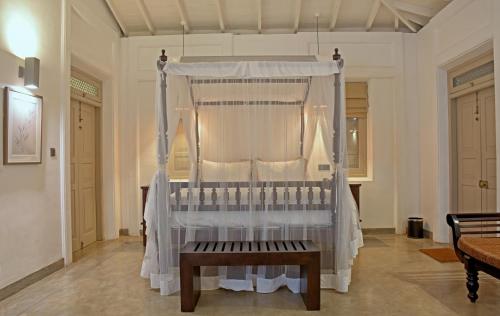 a canopy bed with a bench in a room at Era Beach in Unawatuna