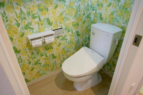 uma casa de banho com WC e papel de parede florido em guesthouse yu -SEVEN Hotels and Resorts- em Yomitan