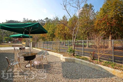 a table and chairs with a green umbrella at XiangLin Homestay in Yuchi