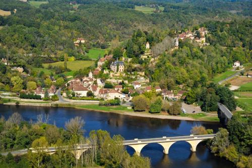 a bridge over a river with a town in the background at Domaine de La Vitrolle in Limeuil