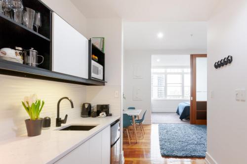 a kitchen with white cabinets and a dining room at Private apartments in a Landmark Heritage Building in Auckland