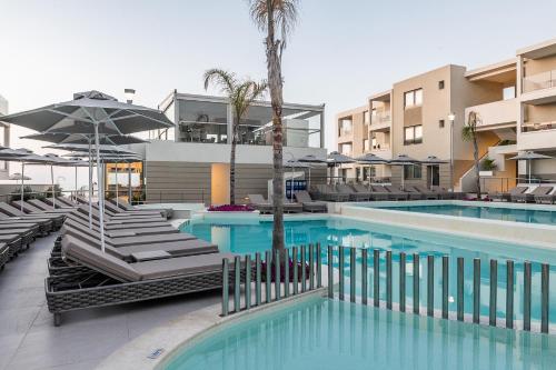 a swimming pool with chairs and umbrellas at a hotel at Porto Platanias Beach Luxury Selection - Adults Only in Plataniás