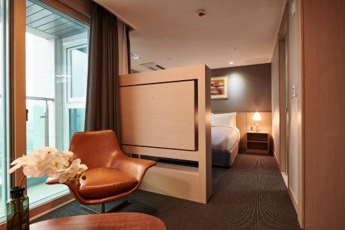 Pokój hotelowy z krzesłem i łóżkiem w obiekcie New Raon Stay w mieście Jinju