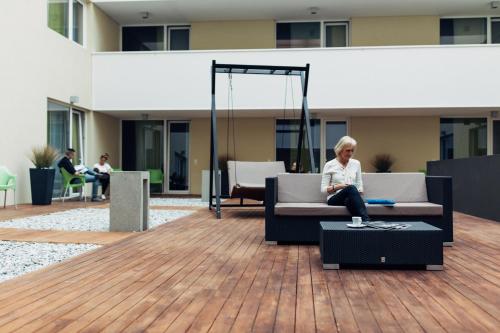 Una donna seduta su un divano in un edificio di harry's home Dornbirn hotel & apartments a Dornbirn