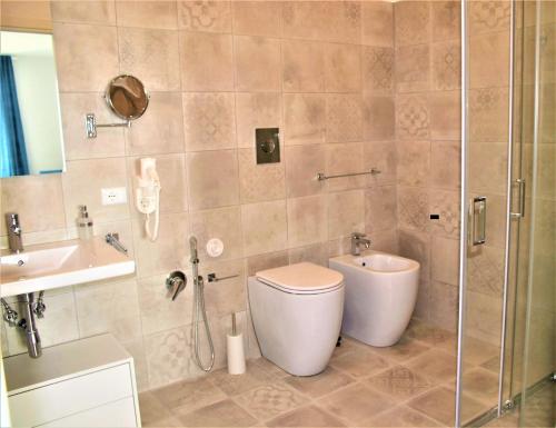 a bathroom with a toilet and a sink and a shower at TOREMARE SUITE MARZAMEMI in Marzamemi
