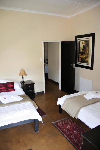 a room with two beds and a table with a picture at Hadassa Guest House in Otjiwarongo