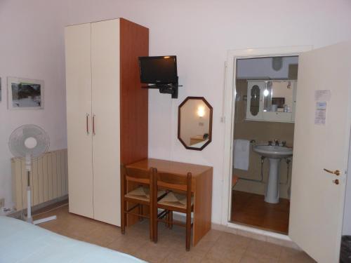 Habitación con 1 dormitorio con lavabo y espejo. en Hotel Fiammetta, en Quercianella