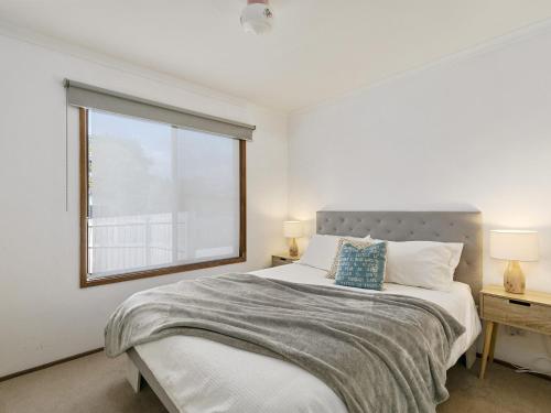 a white bedroom with a large bed and a window at COASTAL BOHO VIBES FREE WIFI & NETFLIX - SURFSIDE in Inverloch
