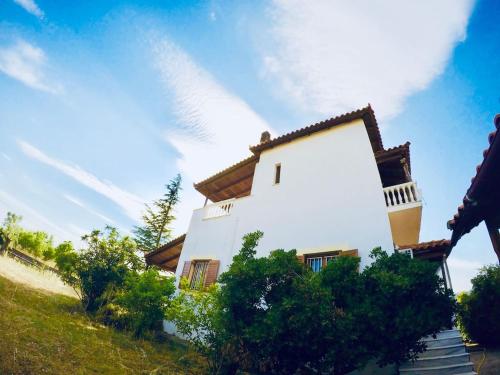a white building on a hill with trees in front at Villa Vasiliki in Palioúras