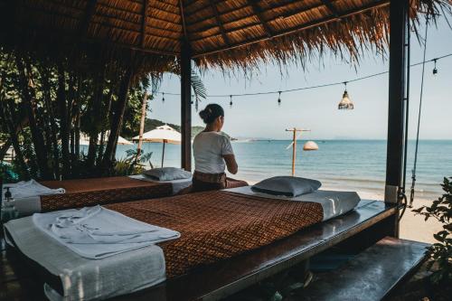 a woman standing next to three beds on the beach at Sea Valley Resort in Lipa Noi