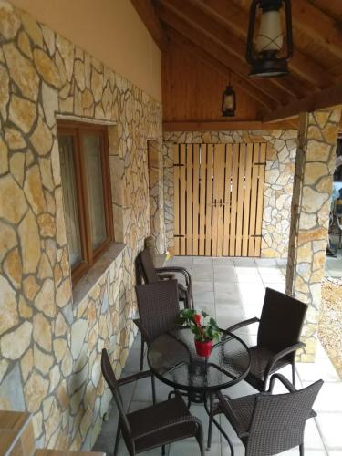 a patio with a table and chairs and a stone wall at Apartmani Sara i Marta in Otočac