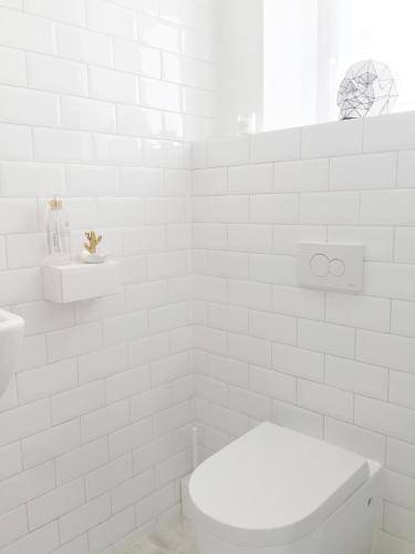 a white bathroom with a toilet and a sink at WHITE HOUSE - silesian loft apartment in Dąbrowa Górnicza
