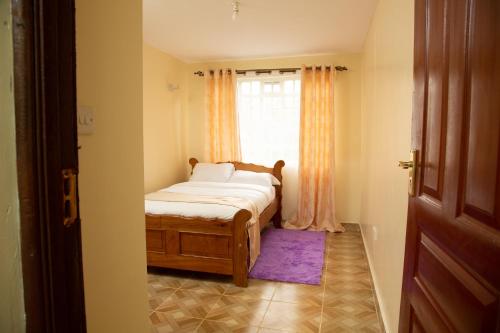 ein kleines Schlafzimmer mit einem Bett und einem Fenster in der Unterkunft Ashville Homes Meru in Meru