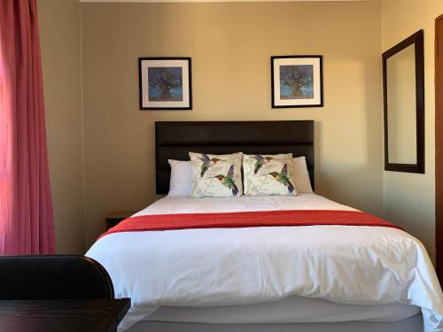 een slaapkamer met een groot bed met 2 kussens bij Malu Guest House in Witbank