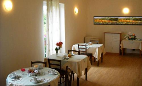 un comedor con 2 mesas y sillas y una pintura en Agriturismo Campi Di Grano, en Roncade
