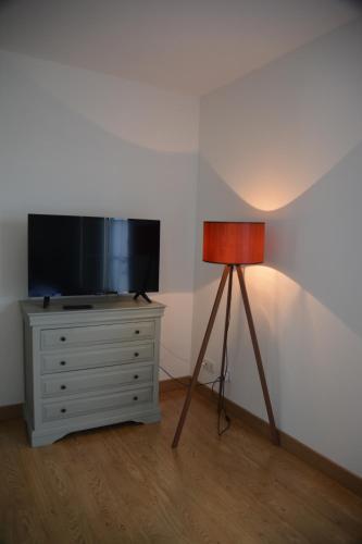 a lamp sitting on a dresser next to a television at la maison du saussoy in Saint-Augustin