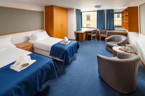 a hotel room with two beds and a table and chairs at Christ's College Cambridge in Cambridge