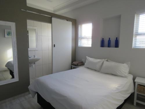 a bedroom with a white bed and a sink at Lagoon Chalets in Walvis Bay