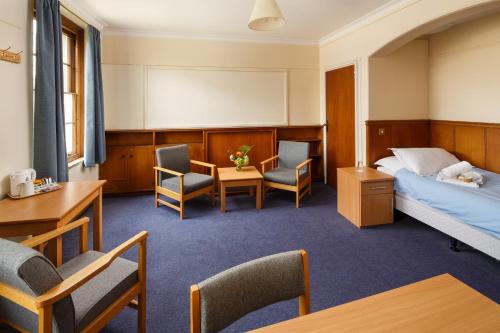 a hotel room with a bed and chairs and a table at Christ's College Cambridge in Cambridge