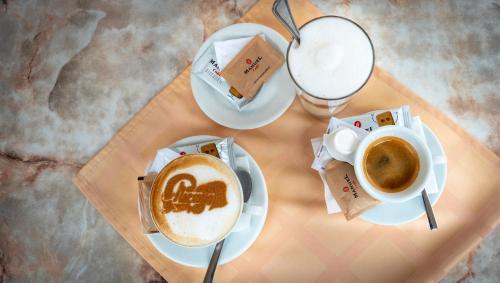 a table with two cups of coffee and a glass of milk at Chicago Vendégház in Szentes