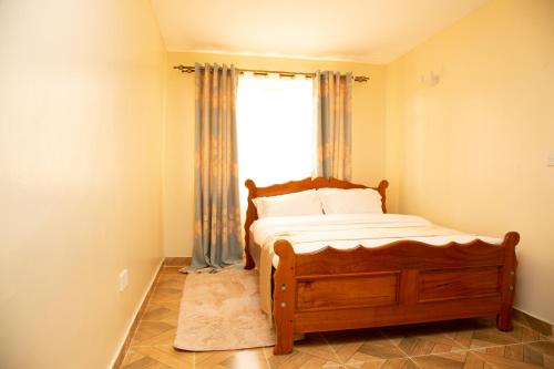 a bedroom with a wooden bed and a window at Ashville Homes Meru in Meru