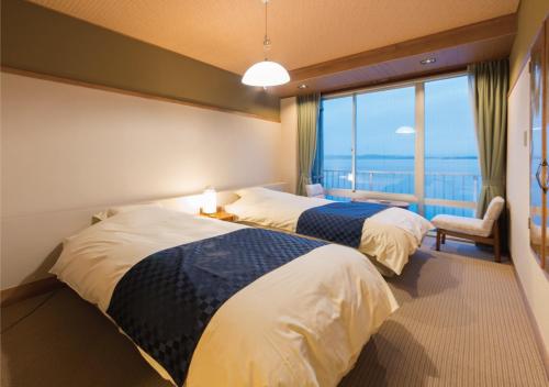 two beds in a room with a large window at Awakan in Sumoto
