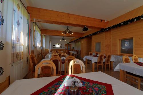 a dining room with white tables and wooden chairs at Dom Wczasowy Dunajec in Biały Dunajec