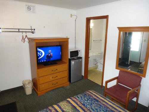 a room with a bedroom with a television and a chair at Tower Motel in Green Bay