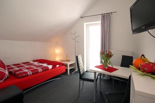 1 dormitorio con cama roja, mesa y ventana en Appart-Hotel Harmonie, en Winterberg