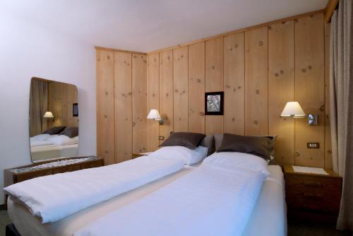 two beds in a room with wooden walls at Ciasa Agá in Corvara in Badia