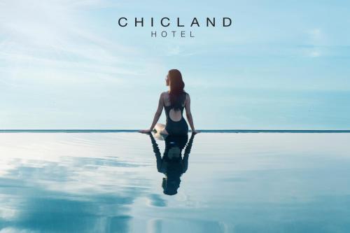 a woman sitting on the water in the ocean at Chicland Boutique Danang Beach Hotel in Da Nang