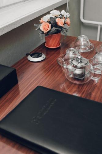 a wooden table with a laptop and flowers on it at Soluxe Hotel Almaty in Almaty