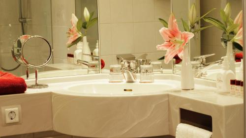 La salle de bains est pourvue d'un lavabo avec miroir et de fleurs roses. dans l'établissement Hotel zur Fürstabtei, à Herford