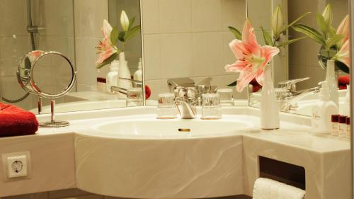 a bathroom with a sink with a mirror and pink flowers at Hotel zur Fürstabtei in Herford