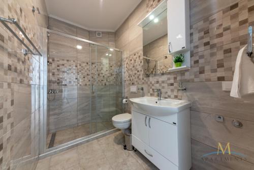 a bathroom with a shower and a toilet and a sink at M Apartments in Bar