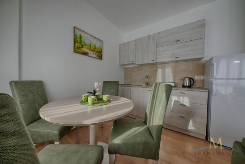 a kitchen with a white table and green chairs at M Apartments in Bar