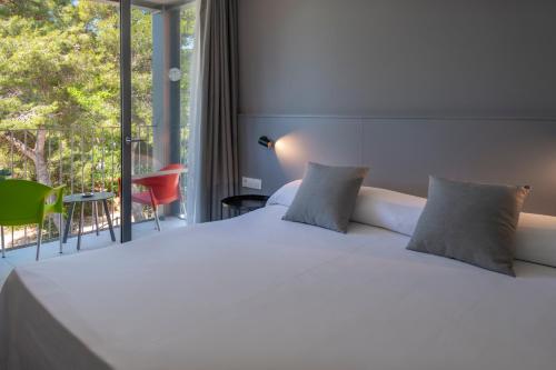 a bed room with a white bedspread and white pillows at GHT Sa Riera in Tossa de Mar