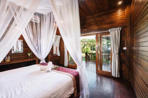 Schlafzimmer mit einem Bett mit weißen Vorhängen in der Unterkunft The Cozy Villas Lembongan in Nusa Lembongan