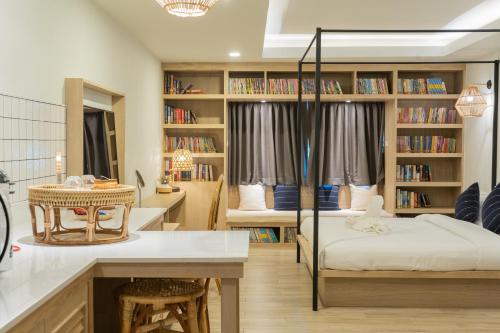 a room with a bed and a desk and bookshelves at Amaka Bed and Breakfast in Chiang Mai