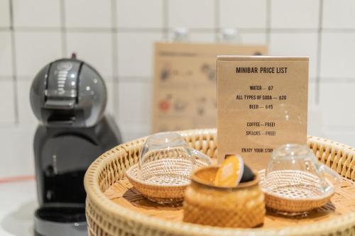 a wicker basket with a coffee maker and two glasses at Amaka Bed and Breakfast in Chiang Mai